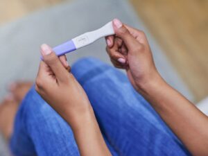 In a serious atmosphere a woman is seen holding pregnancy test grasped in both hands to reveal that she is indeed pregnant.